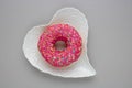 Donut with colorful sprinkles isolated lying on a white plate on gray background. Top view Royalty Free Stock Photo