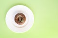 Donut covered with chocolate glaze and sprinkled with green tubes on white plate Royalty Free Stock Photo