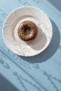 Donut covered with chocolate glaze and sprinkled with green tubes on white plate on blue background Royalty Free Stock Photo