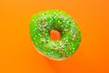 Donut green with sprinkles isolated on orange background, close-up