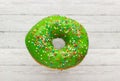 Donut green with sprinkles isolated on wooden background, close-up