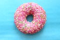 Donut in pink glaze and colored sprinkles on blue background Royalty Free Stock Photo