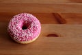 Donut with pink icing on a dark wooden background. Top view. Food concept.