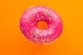 Donut pink with sprinkles isolated on orange background, close-up