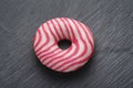 Donut with pink and white strips on black slate background