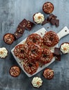 Donut rings and vanilla caramel cupcakes with white and dark chocolate chippings and icing served on board Royalty Free Stock Photo