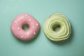 Donuts on turquose background with green, pink icing and white sugar decorations