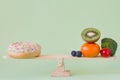 Donut vs. fruits and vegetables on wooden seesaw, diet and calories concept