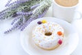 Donut with white icing on the plate of multi-colored jelly beans , the color purple, lavender, white coffee mug Royalty Free Stock Photo