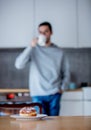 Donut on white plate on wooden table at kitchen and man with cup of coffee Royalty Free Stock Photo