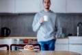 Donut on white plate on wooden table at kitchen and man with cup of coffee Royalty Free Stock Photo