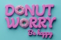 Donut worry be happy inscription with donuts with colorful icing and sprinkles on blue background. Sweet background.