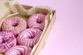 Donuts close-up with pink icing lie in an open box on a pink background. Horizontal background, selective focus Royalty Free Stock Photo