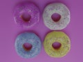 4 donuts with colorful icing on a pink background