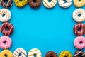 Donuts of different flavors for breakfast frame on blue background top view