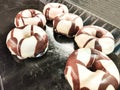 Donuts with a double layer of white chocolate coating and thin stripes of dark chocolate on top. A tender and fluffy dough