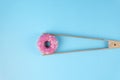 Donuts glaze held by tweezers on blue background