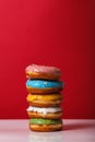 Donuts in multi-colored glaze stacked on top of each other on a red background, copy space. Bakery advertising concept