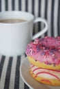 Donuts with pink icing and a cup of coffee with milk on a striped background Royalty Free Stock Photo