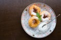 Donuts on the plate. Three donuts with powdered sugar, mint leaf and sour cream on the plate. Wooden background.