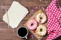 Donuts with sprinkles hearts, cup of coffee and old paper sheet, wooden background, top view Royalty Free Stock Photo