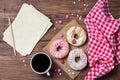 Donuts with sprinkles hearts, cup of coffee and old paper sheet, wooden background, top view Royalty Free Stock Photo