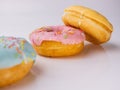 Donuts with sprinkles on the table and a white background. Three types of donuts.