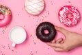 Donuts, sweetmeats candy on pink background. Hand holds donut