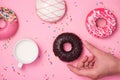 Donuts, sweetmeats candy on pink background. Hand holds donut.