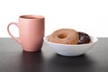 Donuts in a white plate and a mug of coffee stand on