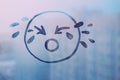 doodle drawn sad face on foggy glass window raindrops blue color concept photo