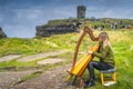 Woman playing harp on the top of iconic Cliffs of Moher, Wild Atlantic Way, Ireland