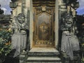 Door or gate to enter into traditional balinese garden architecture detail. Wooden Indonesian gate guarded by stone statues