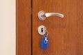 Door handle with inserted key in the keyhole with blue keyholder