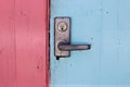 The door handle with a lock at the closed wooden door is pink and blue. Royalty Free Stock Photo