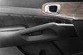 Door handle with power window control buttons of a luxury passenger car. Black perforated leather interior with stitching. Modern