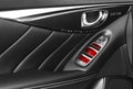 Door handle with red Power window control buttons of a luxury passenger car. Black perforated leather interior with stitching of t