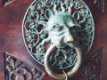 A door knocker is a fixture on the front door of a house. It is made of metal and has the form of a ring, which is