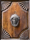 Door knocker in the shape of a face on a carved wooden portal Royalty Free Stock Photo