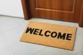 Door mat with word Welcome on floor near entrance, above view