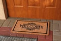 Door mat with word Welcome on street tiles near entrance