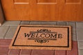 Door mat with word Welcome on street tiles near entrance