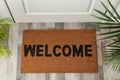Door mat with word Welcome on wooden floor in hall, top view Royalty Free Stock Photo