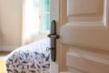 Door open, blur elegant hotel room, bedroom interior. Retro door knob on white door, close up Royalty Free Stock Photo