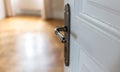 Door open close up. Retro doorknob on white door, blur floor parquet, classy room interior Royalty Free Stock Photo