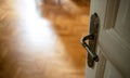 Door open close up. Retro doorknob on white door, blur floor parquet, classy house interior Royalty Free Stock Photo