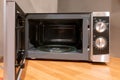 Door open microwave oven on wooden table in kitchen