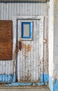 A door with peeling white and blue paint on an abandoned wood building Royalty Free Stock Photo