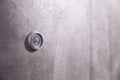 Door peephole on a dark gray metal door.