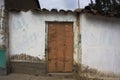 poor and abandoned house with dirty adobe wall dirth with closed metal door street and sidewalk blue wal Royalty Free Stock Photo